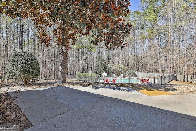 view of patio / terrace with an outdoor pool, a forest view, and fence