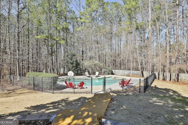 view of pool featuring a patio, a fenced in pool, fence, and a forest view