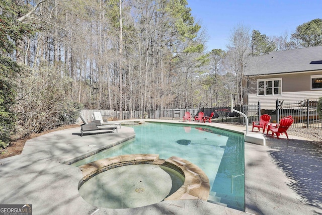 view of swimming pool featuring a patio, a pool with connected hot tub, and fence