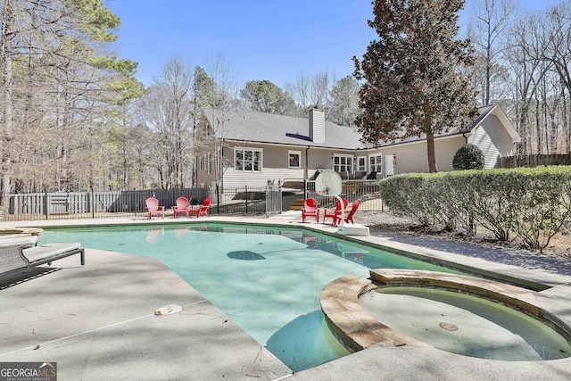 view of swimming pool with a pool with connected hot tub, a patio, and fence