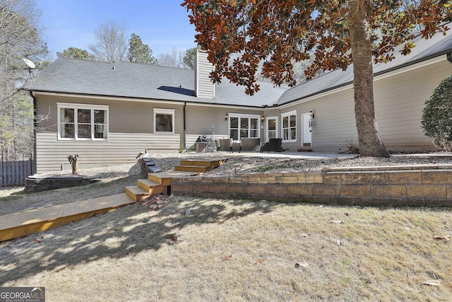 rear view of property with a patio area, a chimney, and fence