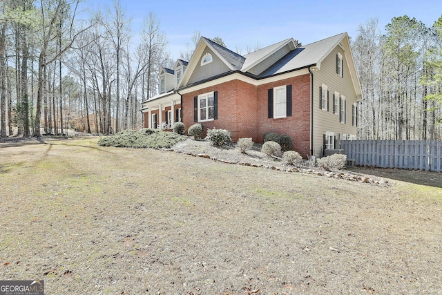 view of side of property featuring brick siding, a chimney, and fence