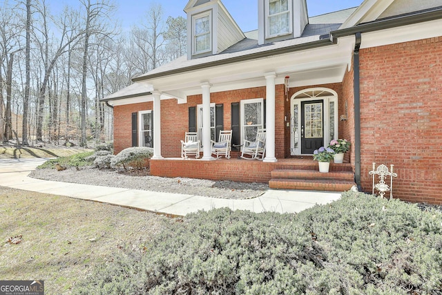 doorway to property with brick siding and covered porch