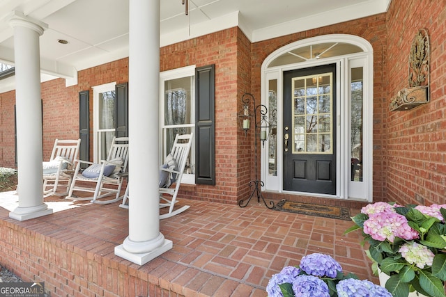 doorway to property featuring brick siding and covered porch