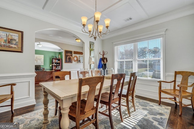 dining room with arched walkways, wood finished floors, visible vents, and wainscoting