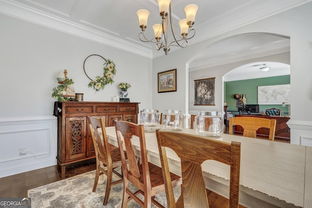 dining room featuring dark wood finished floors, ornamental molding, a chandelier, and wainscoting