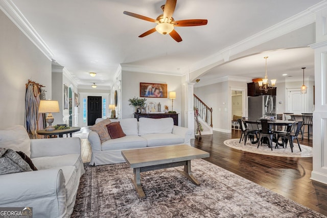 living room with ornamental molding, dark wood finished floors, arched walkways, decorative columns, and stairs