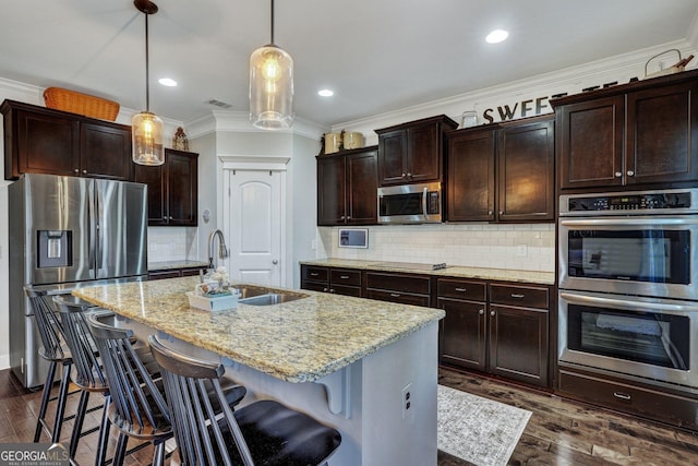 kitchen featuring dark wood-style flooring, a sink, stainless steel appliances, a kitchen bar, and backsplash