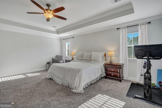 carpeted bedroom featuring baseboards, a raised ceiling, visible vents, and crown molding