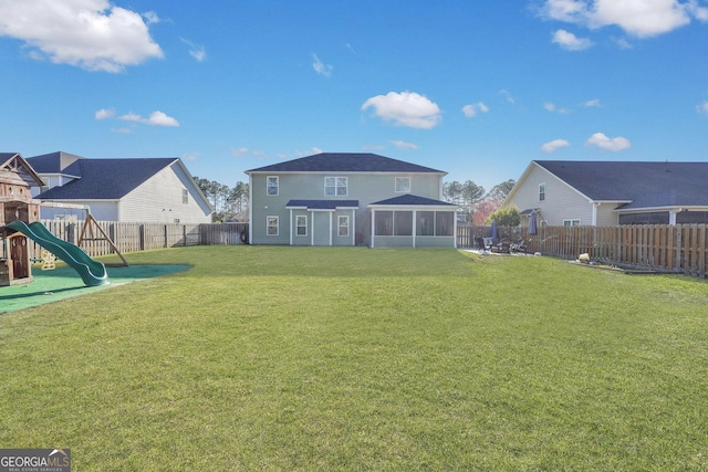 view of yard with a playground, a fenced backyard, and a sunroom