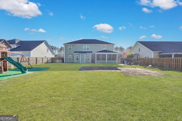 rear view of property with a lawn, a playground, a fenced backyard, and a sunroom