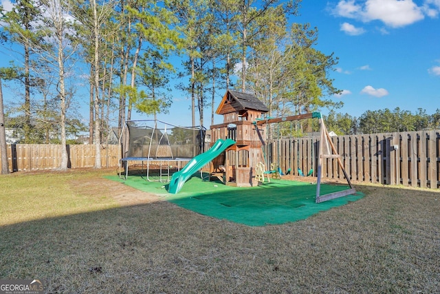 community playground featuring a yard, a fenced backyard, and a trampoline