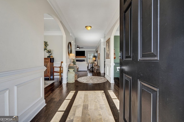 entryway with a decorative wall, ornamental molding, a fireplace, and hardwood / wood-style floors