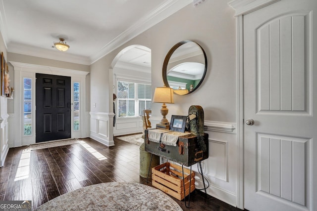 entryway featuring a wainscoted wall, dark wood-type flooring, ornamental molding, arched walkways, and a decorative wall