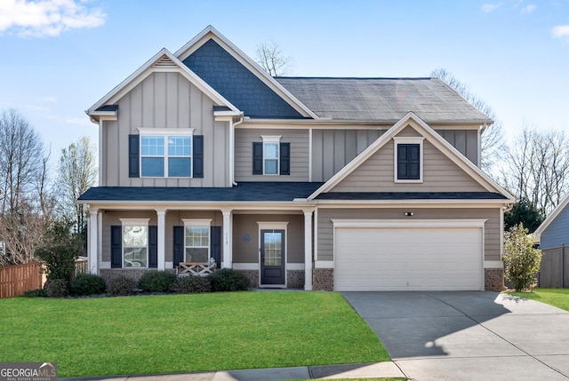 craftsman-style home featuring a front lawn, fence, board and batten siding, an attached garage, and driveway