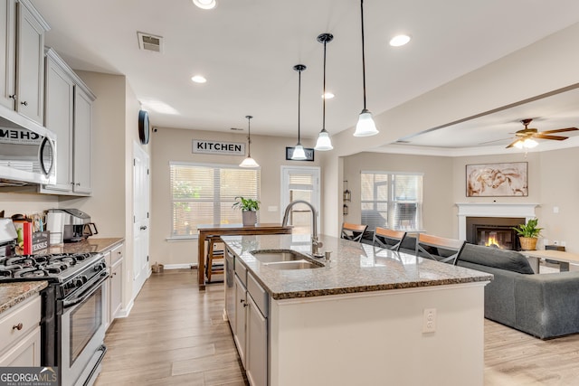 kitchen with visible vents, open floor plan, light wood-type flooring, a sink, and appliances with stainless steel finishes