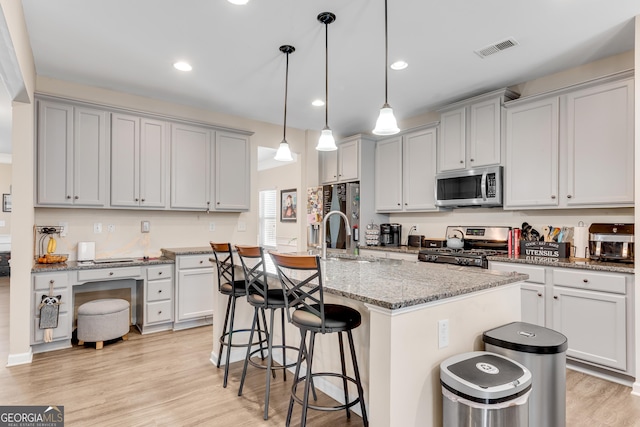 kitchen featuring visible vents, a sink, appliances with stainless steel finishes, and a kitchen bar