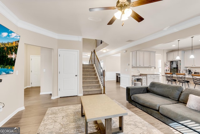 living area with crown molding and light wood-type flooring