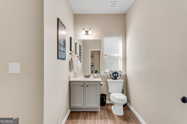 bathroom featuring vanity, visible vents, wood finished floors, toilet, and baseboards