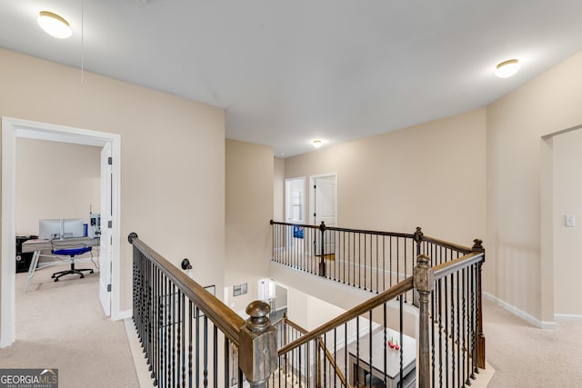 hallway with baseboards, light carpet, attic access, and an upstairs landing