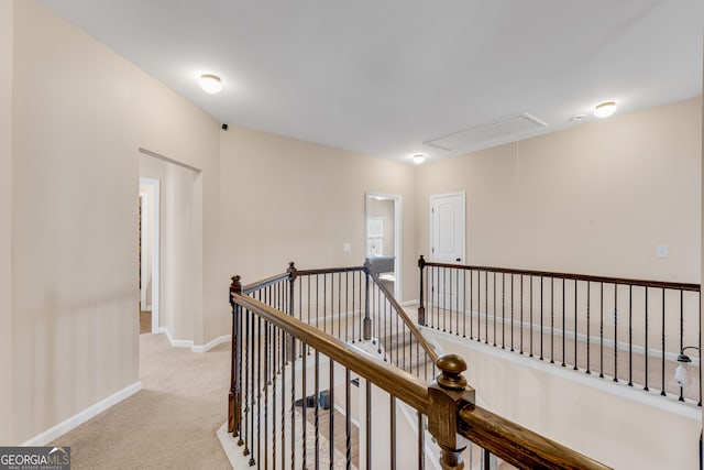 hall featuring baseboards, an upstairs landing, carpet, and attic access