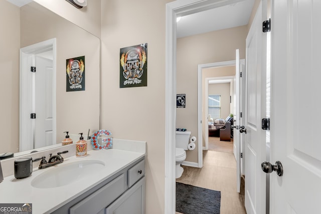 bathroom featuring vanity, baseboards, toilet, and wood finished floors