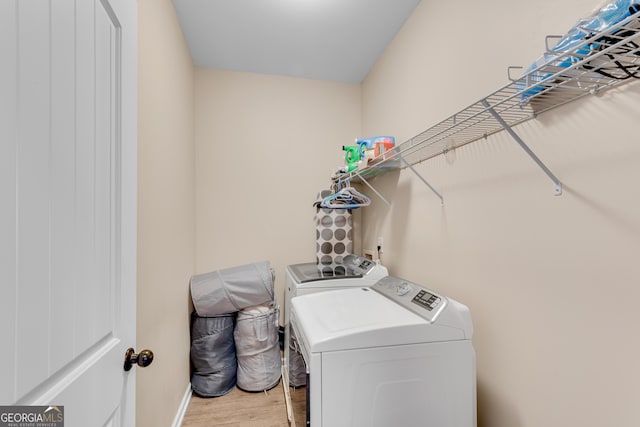 laundry area featuring laundry area, light wood-type flooring, baseboards, and washing machine and clothes dryer