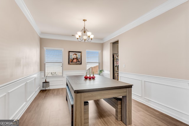 dining area featuring ornamental molding, wood finished floors, and a chandelier