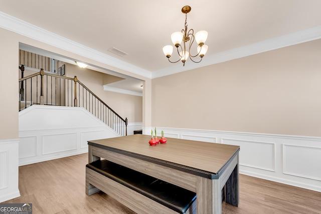 dining space with stairway, a decorative wall, wood finished floors, and a notable chandelier