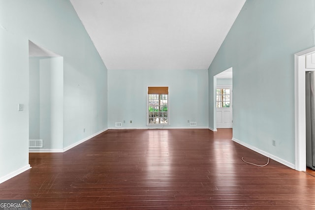 empty room featuring visible vents, high vaulted ceiling, baseboards, and wood finished floors