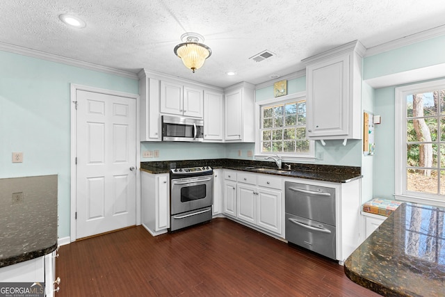 kitchen with a sink, visible vents, white cabinetry, and stainless steel appliances