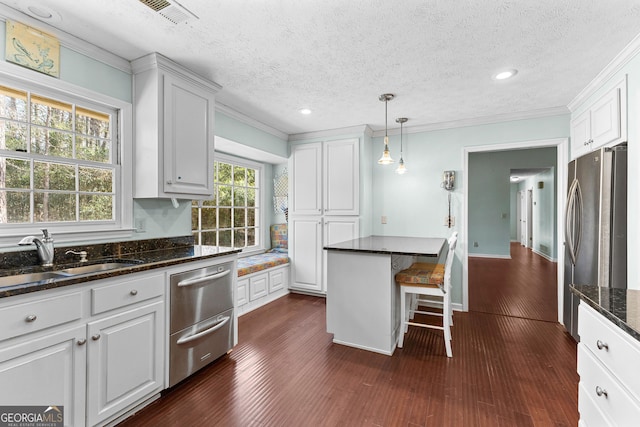 kitchen featuring white cabinetry, crown molding, freestanding refrigerator, and a sink