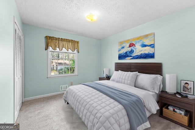 carpeted bedroom featuring a closet, visible vents, a textured ceiling, and baseboards