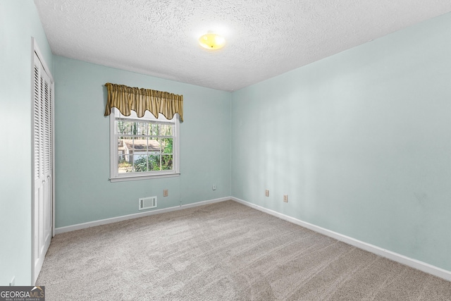 unfurnished bedroom with a closet, visible vents, carpet flooring, and a textured ceiling