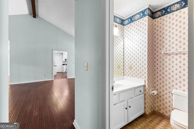 bathroom featuring baseboards, toilet, lofted ceiling with beams, wood finished floors, and a textured ceiling