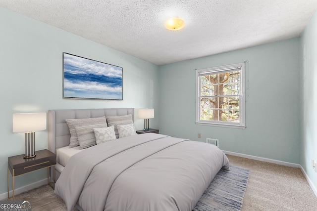 carpeted bedroom with baseboards, visible vents, and a textured ceiling