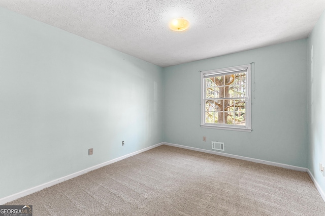 carpeted spare room with baseboards, visible vents, and a textured ceiling