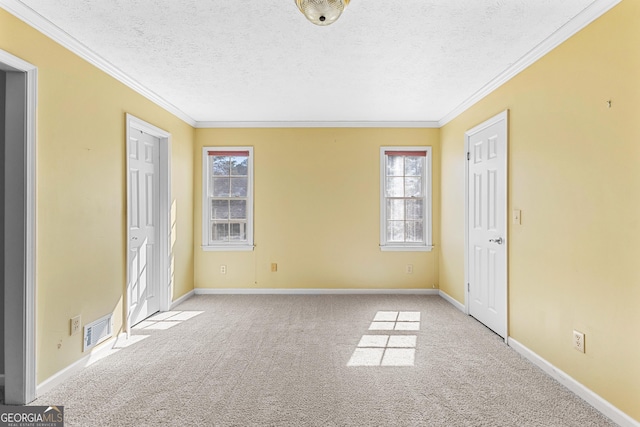 carpeted empty room featuring visible vents, baseboards, a textured ceiling, and crown molding