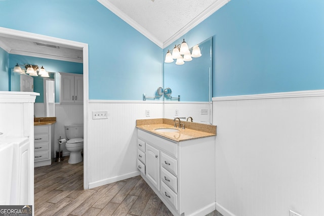 bathroom with crown molding, a wainscoted wall, vanity, wood finished floors, and a textured ceiling