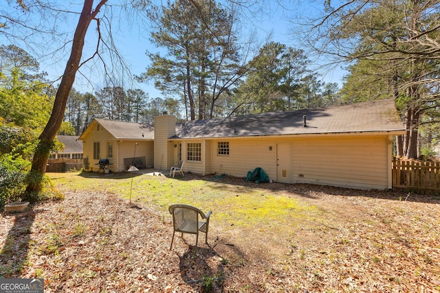 back of house with a chimney, a yard, and fence