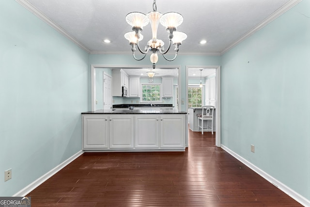 kitchen with dark countertops, stainless steel microwave, dark wood-type flooring, baseboards, and a chandelier