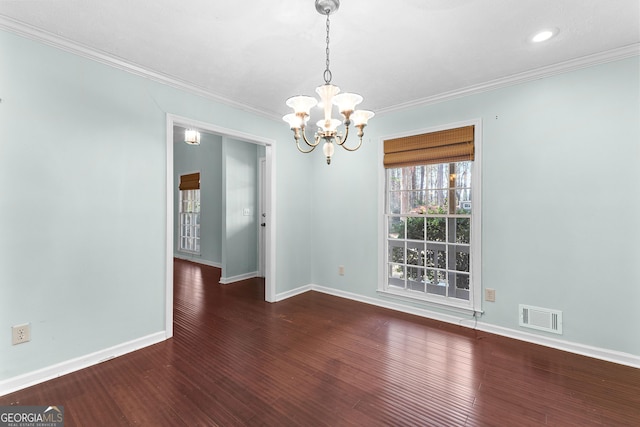 spare room featuring an inviting chandelier, crown molding, wood finished floors, and visible vents