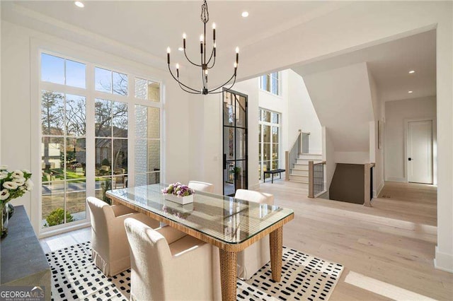 dining room featuring stairs, a notable chandelier, plenty of natural light, and light wood finished floors