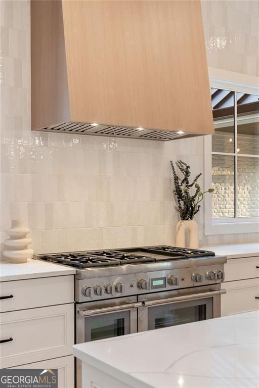 kitchen featuring decorative backsplash, custom exhaust hood, double oven range, and light countertops