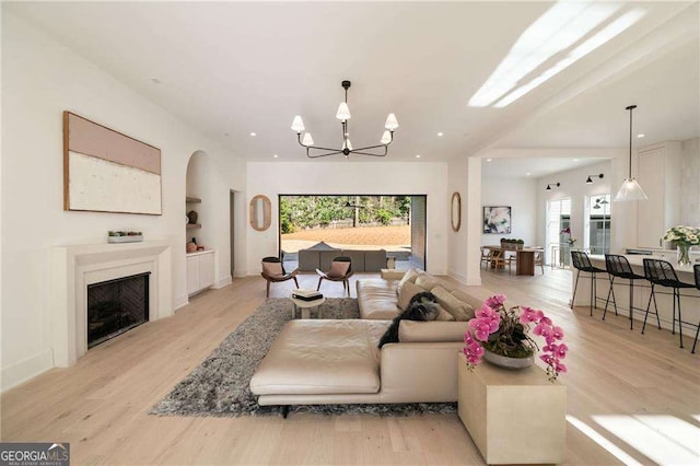 living room with recessed lighting, a notable chandelier, light wood-style flooring, and a fireplace