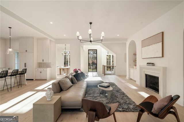 living room featuring a notable chandelier, a fireplace, light wood-type flooring, and a wealth of natural light