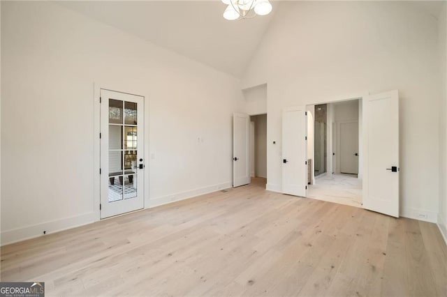 unfurnished bedroom with light wood-type flooring, baseboards, high vaulted ceiling, and access to exterior