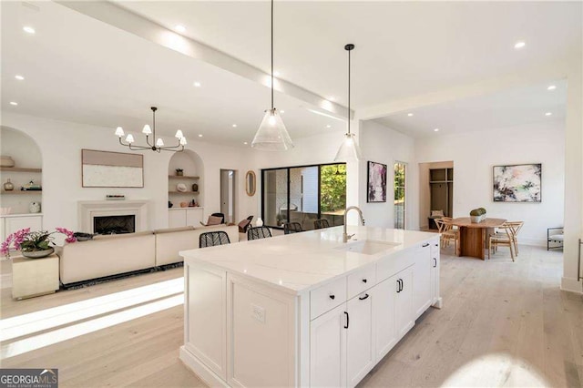 kitchen featuring light wood finished floors, beam ceiling, built in features, and a sink