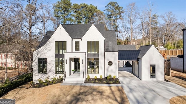 view of front facade featuring driveway, metal roof, a standing seam roof, and fence