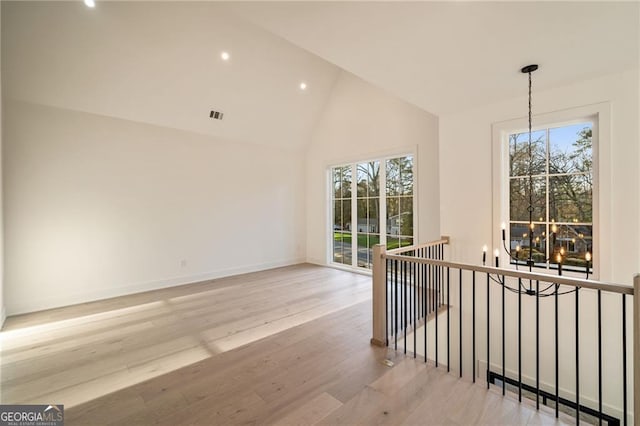 unfurnished room with wood finished floors, a healthy amount of sunlight, baseboards, and high vaulted ceiling